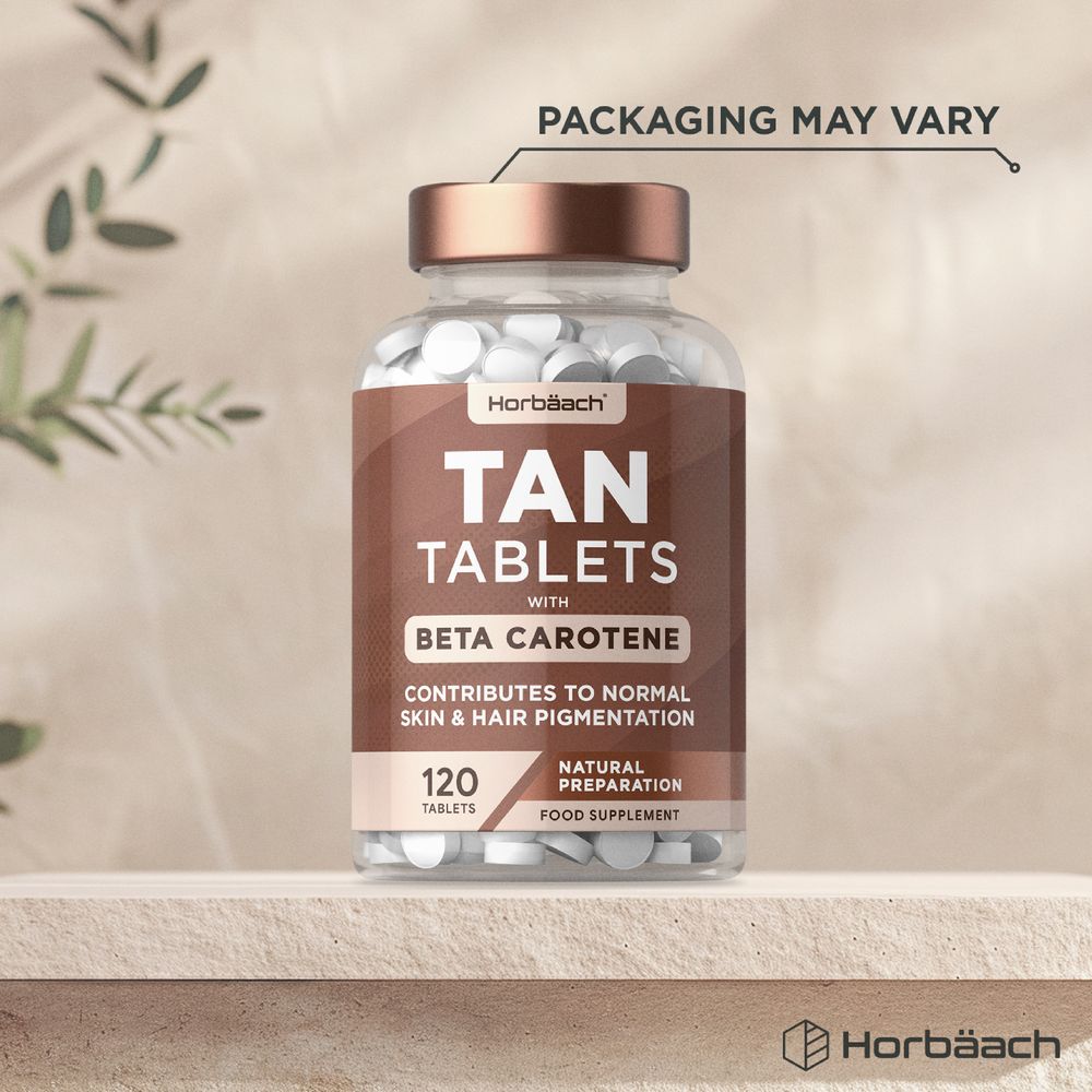 A hand holding a quantity of 120 tan tablets that contain beta carotene, carefully weighed to show vitamin supplement measurement.