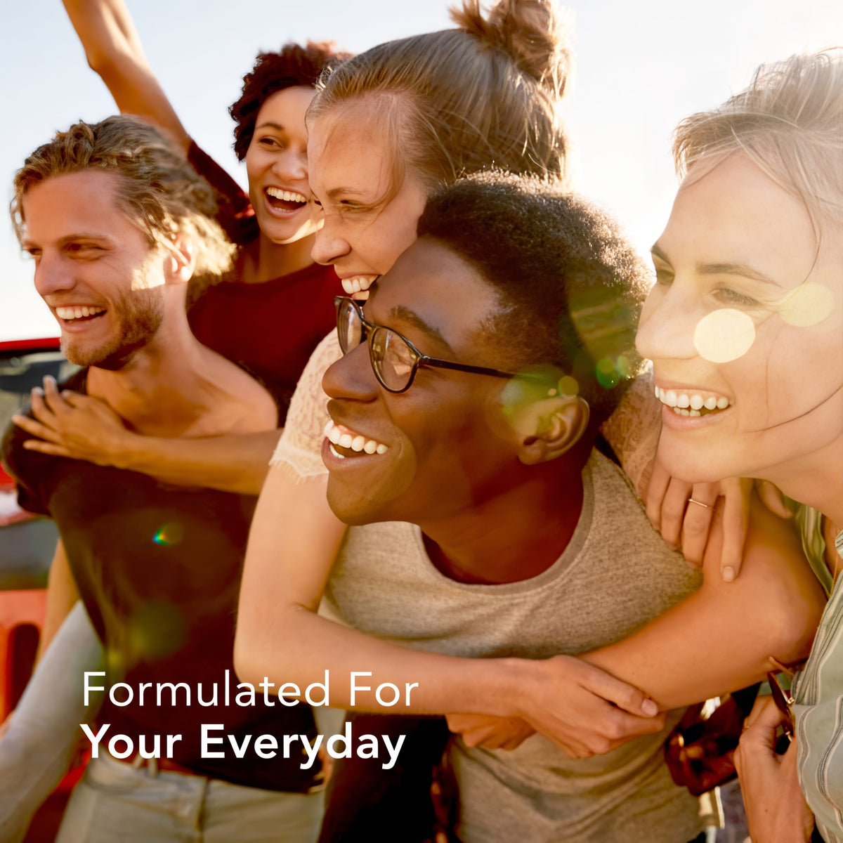 Group of diverse young adults smiling and embracing outdoors, holding Turmeric, Ginger, and Black Pepper.