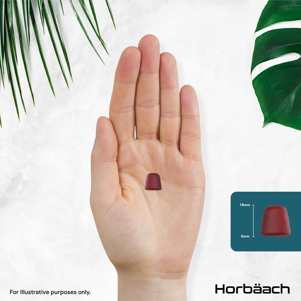 A single red multivitamin gummy, 18mm tall, is held in an open hand.