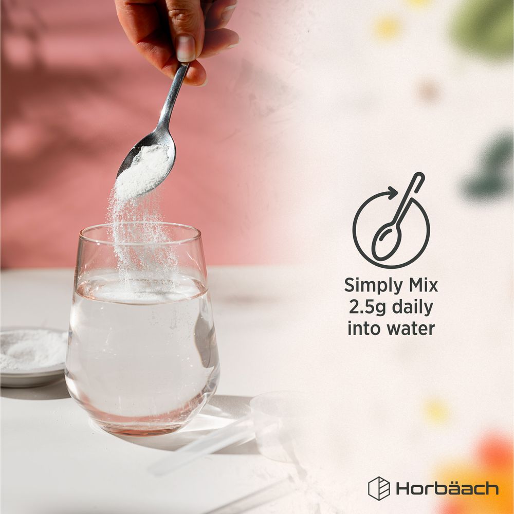 An adult hand pours Magnesium Citrate powder from a spoon into a glass of water, capturing a lifestyle moment.