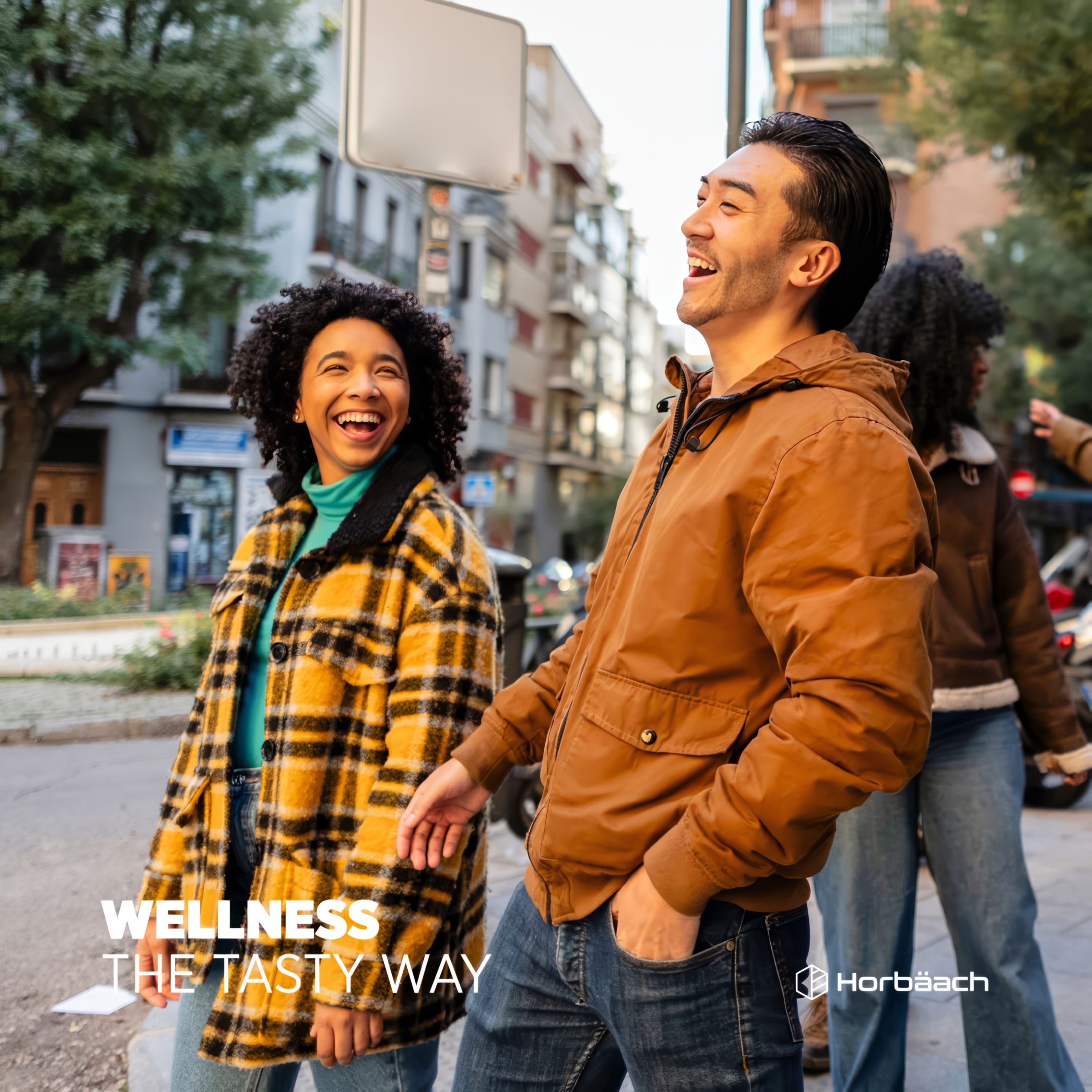 Two young adults joyfully laugh and walk on a city street, promoting Biotin Gummies.