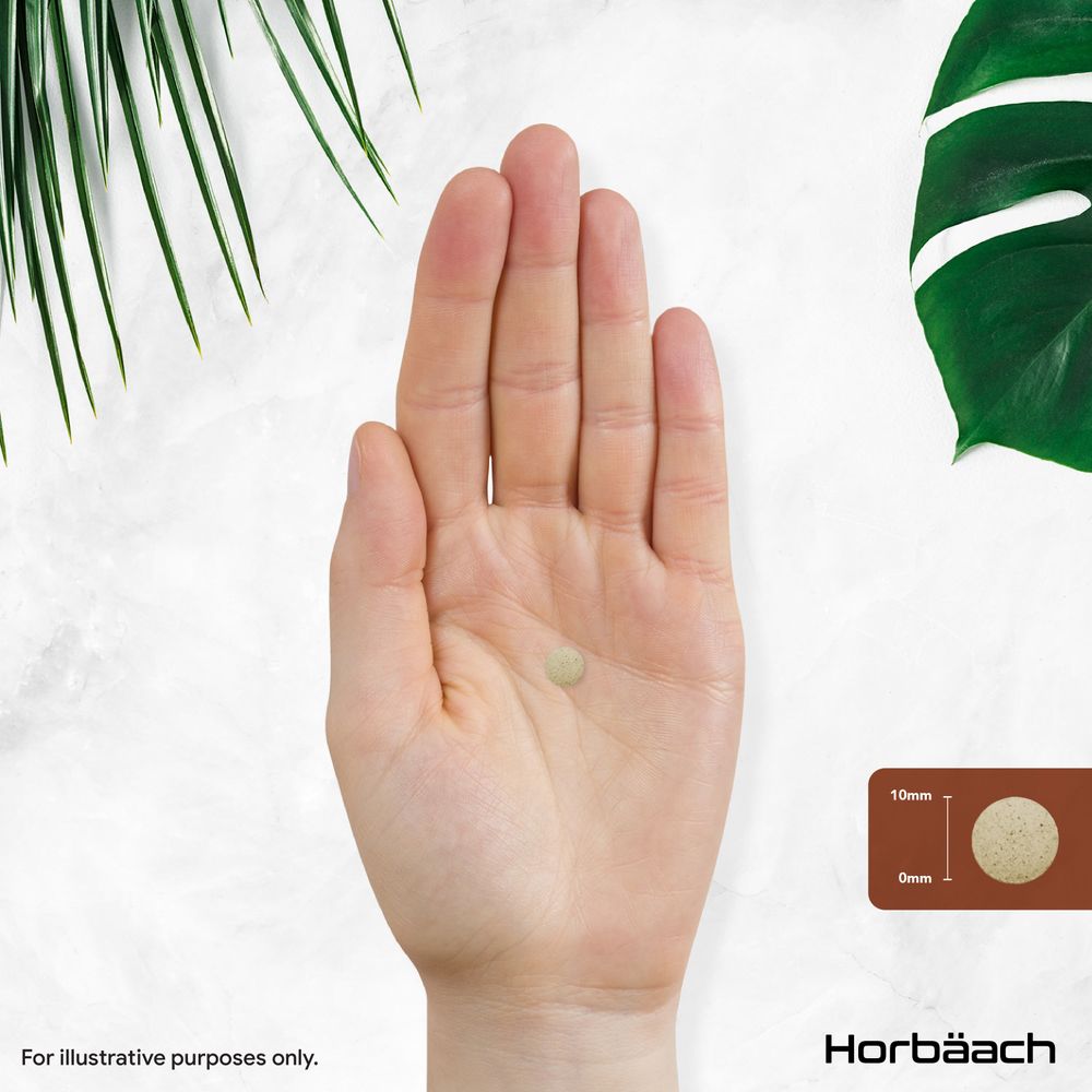 A single 10mm vegan tablet rests on an open palm, showcasing its size and form in a detailed view.