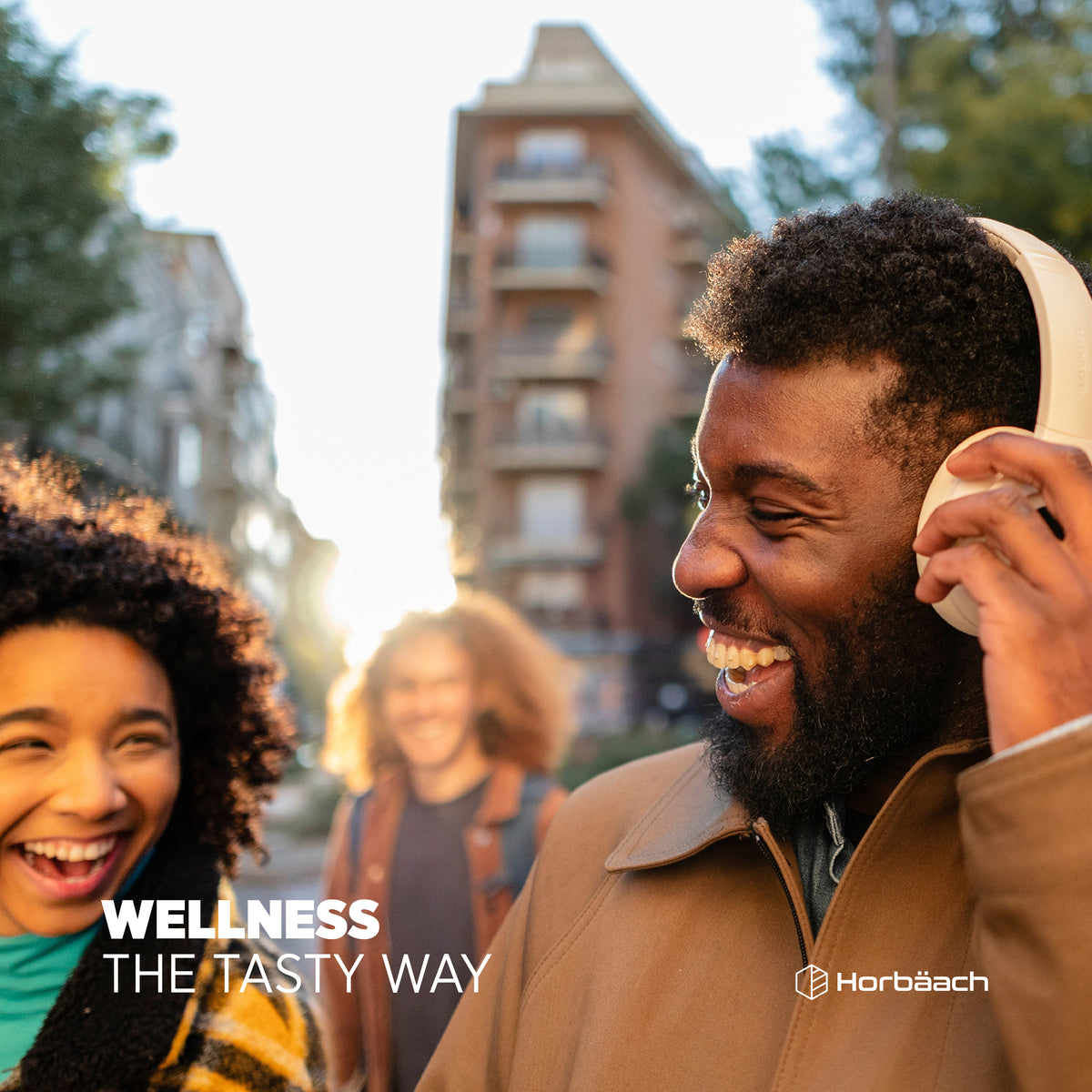 Young adults laughing and walking outdoors with text 'WELLNESS THE TASTY WAY' for Folic Acid 400ug Vegan Gummies.